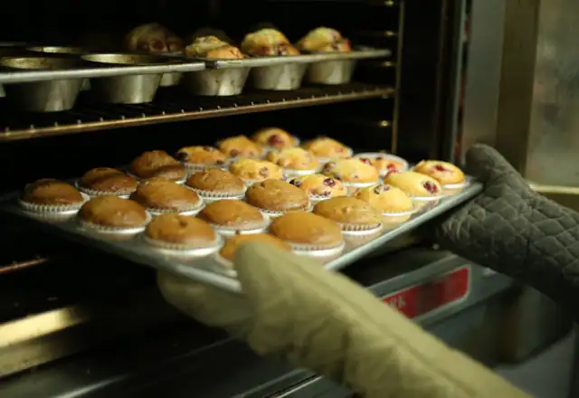 Baker holding a tray of fresh muffins for starting a bakery business