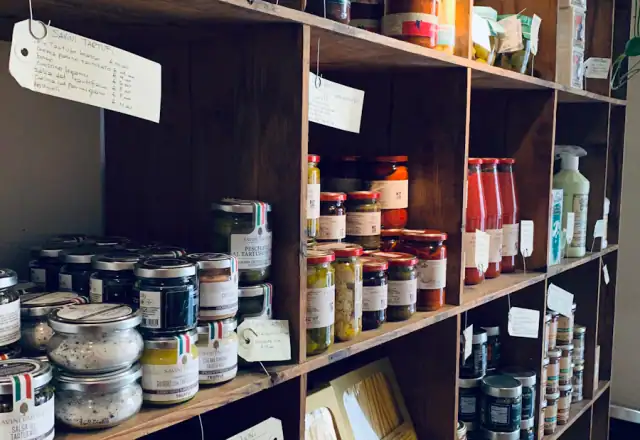 Assorted glass jars on a wooden shelf for dry ingredient and packaging storage