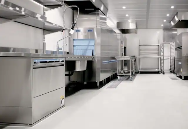 Commercial kitchen with stainless steel dishwashing equipment and metal shelving units for equipment and facilities