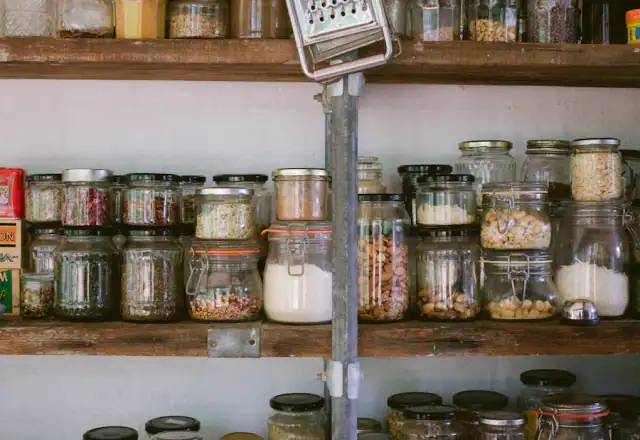 Glass jars on white wooden shelves for dry ingredient and packaging storage