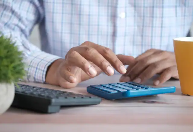 Person using a calculator at a desk for kitchen rental faqs