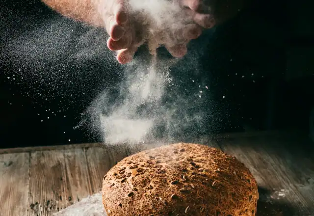 Loaf of bread being dusted with flour for ovens and baking equipment