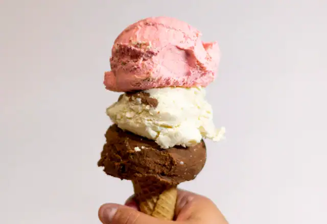 Hand holding a scoop of ice cream for freezer storage