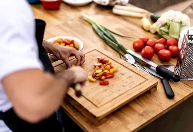 Person cutting vegetables on a cutting board for kitchen rental for personal chefs