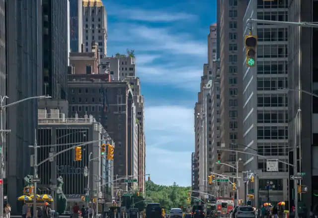 Tall buildings along a wide city street under blue sky for contact us