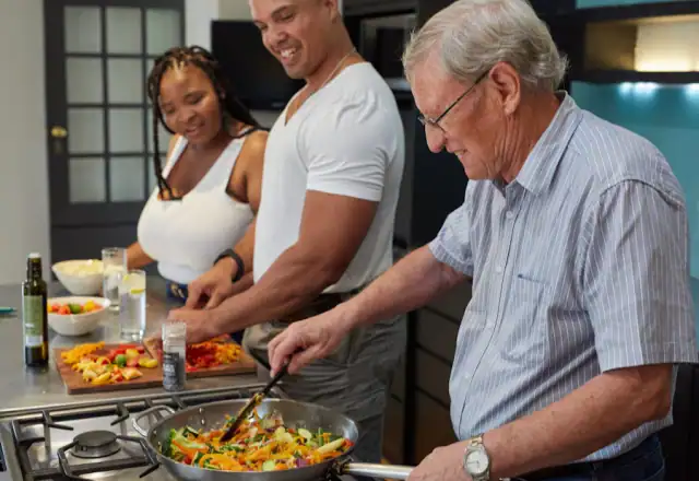 Group of people standing around a stove preparing food for batch coding and product traceability