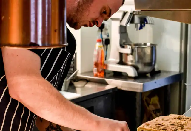 Cook preparing food on a plate in a kitchen for kitchen rental faqs