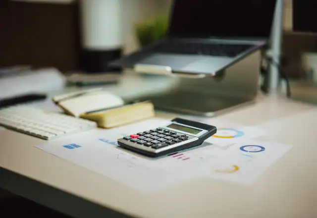 Calculator on a table next to a laptop for request a rental quote