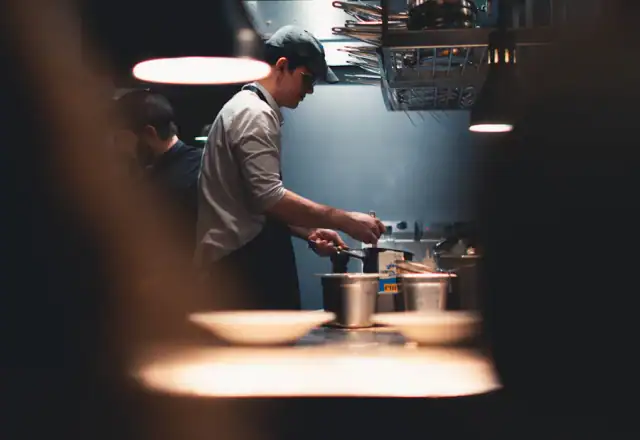 Chef cooking in a professional kitchen at night for about us