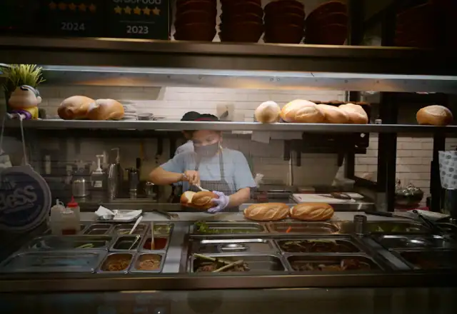Cook assembling food at a counter with ingredients for setting up a meal prep packing station
