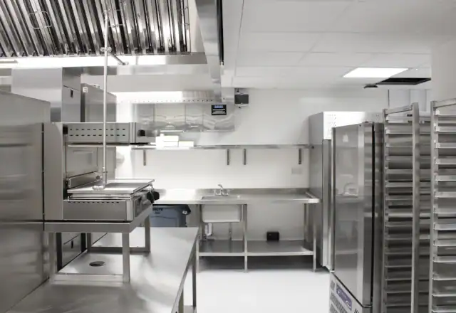 Commercial kitchen with stainless steel appliances and metal shelving for about us