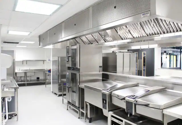 Commercial kitchen with stainless steel appliances and a large ventilation hood for choosing the right kitchen size